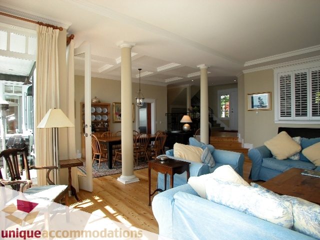 Spacious living room with high ceilings, large windows, and a cozy blue sofa. - 3586 Creery Ave, West Vancouver