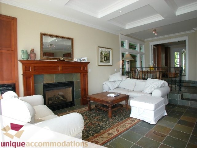 Spacious living room with a fireplace, white couches, and a patterned rug. - 3586 Creery Ave, West Vancouver