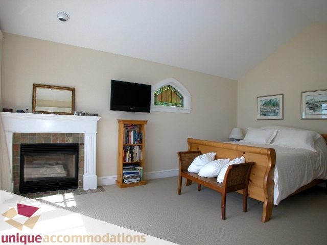 Spacious bedroom with a cozy fireplace, large windows, and a comfortable bed setup. - 3586 Creery Ave, West Vancouver