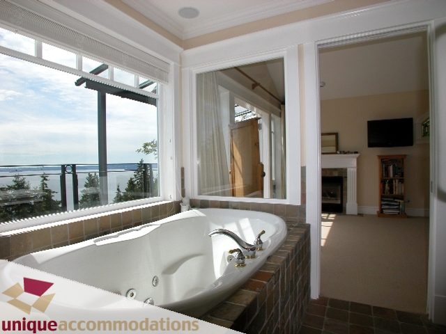 Spacious master bathroom with a large soaking tub, city view, and modern fixtures. - 3586 Creery Ave, West Vancouver