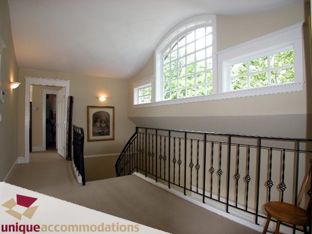 Staircase with arched windows and black iron railings leading to upper level. - 3586 Creery Ave, West Vancouver
