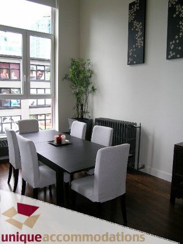 Dining area with black table, white chairs, city view, hardwood floors. - PH2 - 869 Beatty Street, Vancouver Downtown