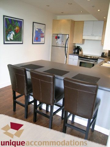 Furnished kitchen with modern appliances and wooden bar stools. - PH2 - 869 Beatty Street, Vancouver Downtown
