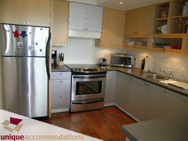 Bright kitchen with stainless steel appliances, hardwood floors, and light wood cabinets. - PH2 - 869 Beatty Street, Vancouver Downtown