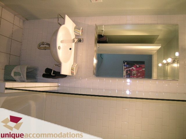 Furnished bathroom with white tiles and a large mirror reflecting the room. - PH2 - 869 Beatty Street, Vancouver Downtown