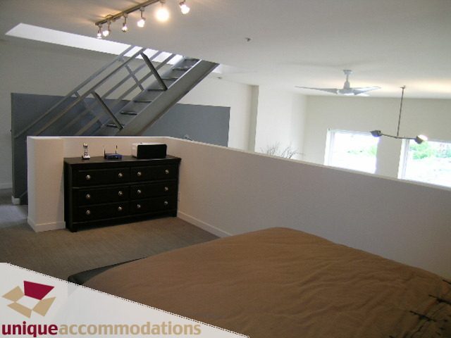 Bright bedroom with a large bed, black dresser, and a skylight. - PH2 - 869 Beatty Street, Vancouver Downtown