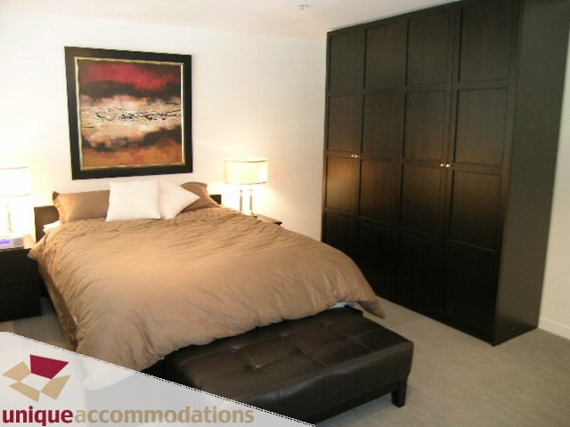 Furnished 1-bedroom penthouse with modern decor, dark wood cabinets, and a comfortable bed. - PH2 - 869 Beatty Street, Vancouver Downtown