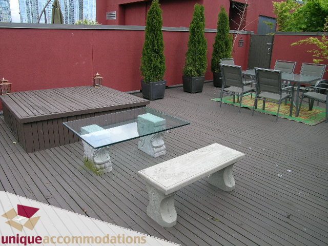 Furnished patio with wooden deck, glass tables, and outdoor seating. - PH2 - 869 Beatty Street, Vancouver Downtown