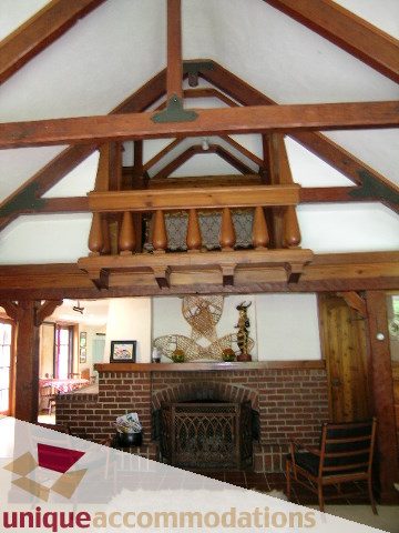 Furnished living room with exposed wooden beams and brick fireplace. - 419 Inglewood ave, West Vancouver
