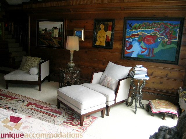 Furnished living room with wooden walls, colorful artwork, and patterned rug. - 419 Inglewood ave, West Vancouver