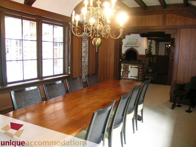 Dining room with large wooden table, chandelier, and brick fireplace. - 419 Inglewood ave, West Vancouver