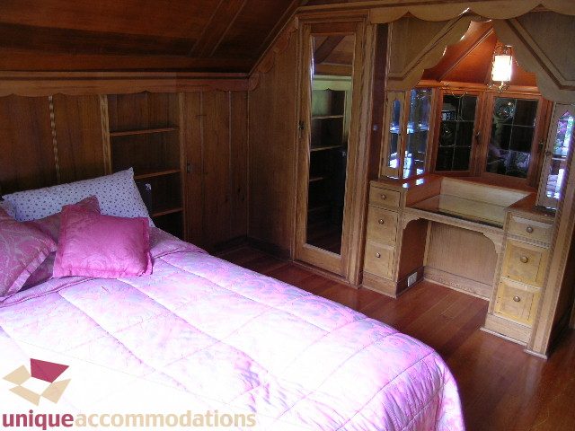 Furnished bedroom with wooden furniture, pink bedding, and hardwood floors. - 419 Inglewood ave, West Vancouver