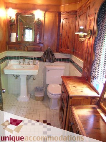Furnished bathroom with wooden cabinets, pedestal sink, and checkered tile floor. - 419 Inglewood ave, West Vancouver