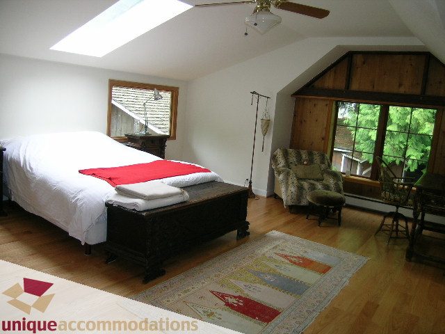 Bright bedroom with hardwood floors, large windows, and a cozy bed setup. - 419 Inglewood ave, West Vancouver