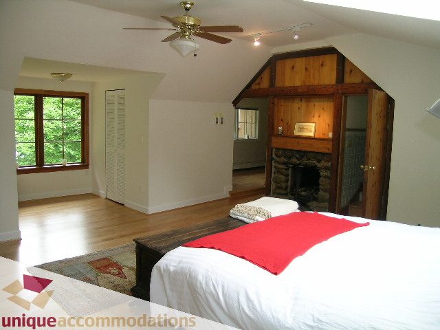 Spacious bedroom with wooden beams, red throw, and hardwood floors. - 419 Inglewood ave, West Vancouver