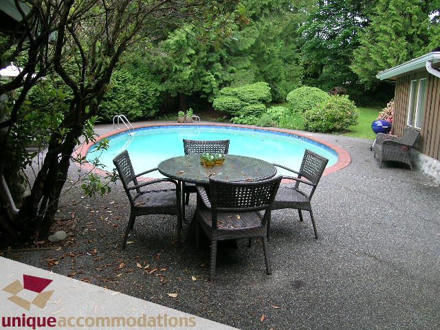 Furnished patio with a round table, chairs, and a swimming pool surrounded by lush greenery. - 419 Inglewood ave, West Vancouver