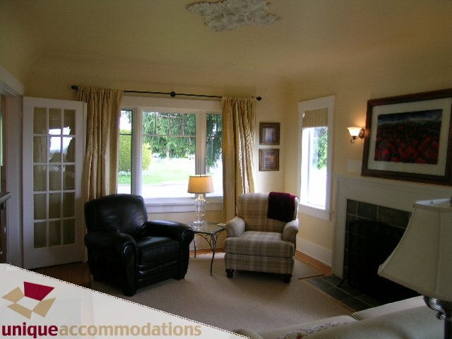 Furnished living room with large windows, cozy seating, and a fireplace. - 1505 Grand Blvd., North Vancouver