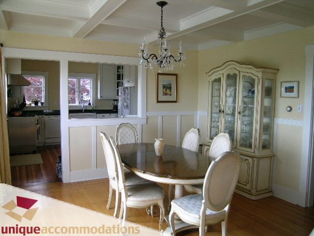 Furnished dining area with chandelier, hardwood floors, and kitchen in the background. - 1505 Grand Blvd., North Vancouver