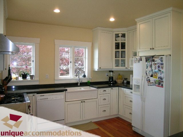 Bright kitchen with white cabinets, black countertops, and hardwood floors. - 1505 Grand Blvd., North Vancouver