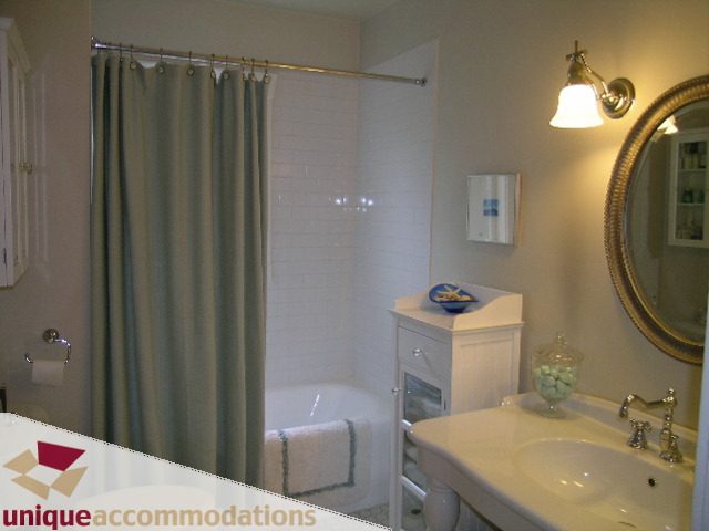 Bathroom with white sink, mirror, and shower curtain. - 1505 Grand Blvd., North Vancouver
