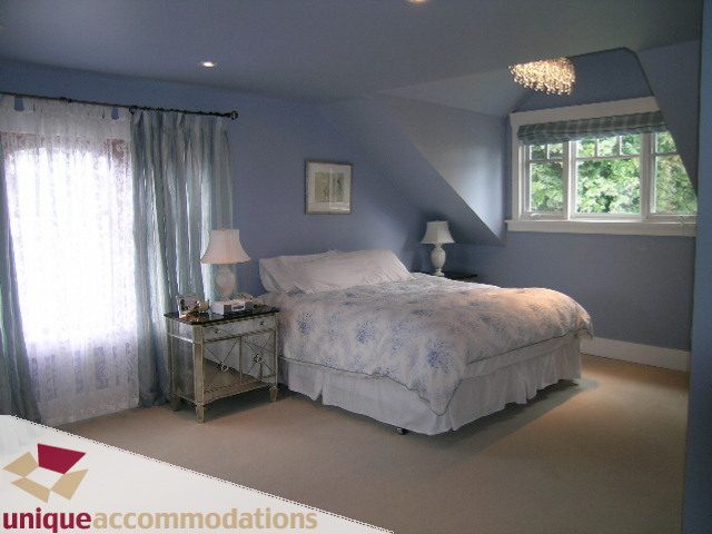 Spacious bedroom with two twin beds, blue walls, and large window with view. - 1505 Grand Blvd., North Vancouver