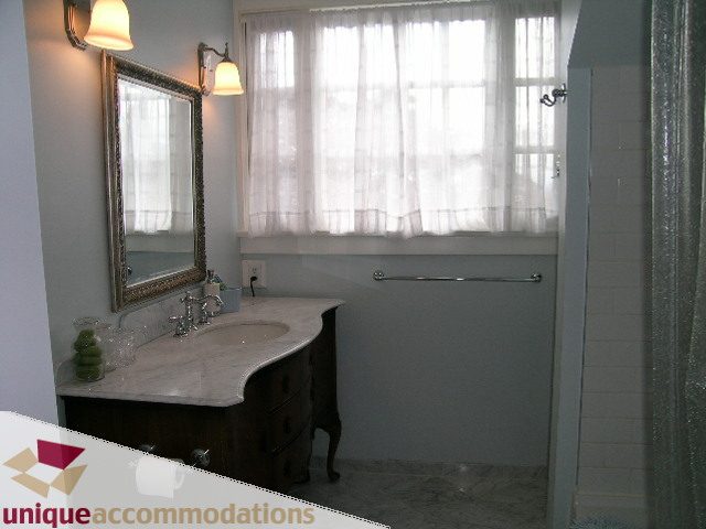 Bathroom with marble countertops and a large window with sheer curtains. - 1505 Grand Blvd., North Vancouver
