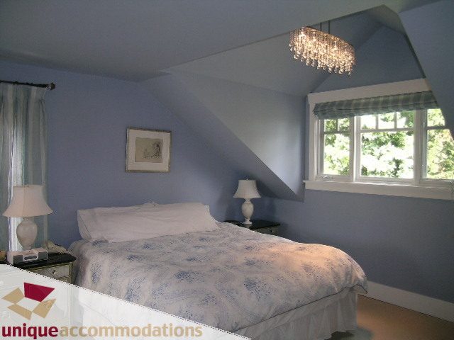 Bright bedroom with sloped ceiling, chandelier, and natural light from windows. - 1505 Grand Blvd., North Vancouver