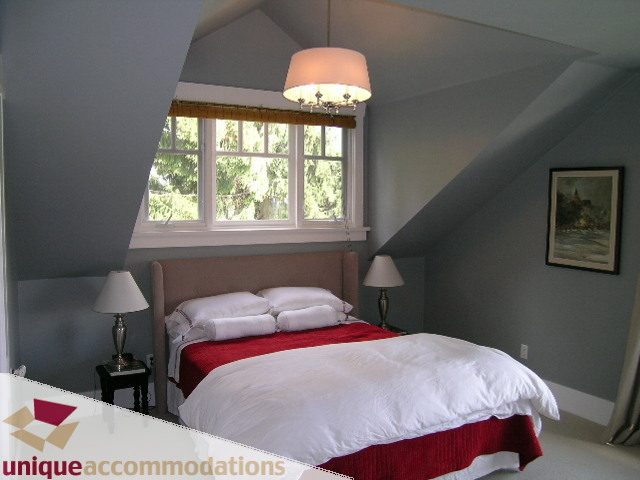 Bright bedroom with sloped ceiling, large window, and red accents. - 1505 Grand Blvd., North Vancouver