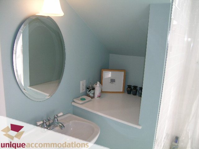 Bright bathroom with light blue walls, white sink, and mirror. - 1505 Grand Blvd., North Vancouver