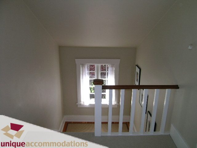Staircase leading to upper level with natural light and white railings. - 1505 Grand Blvd., North Vancouver