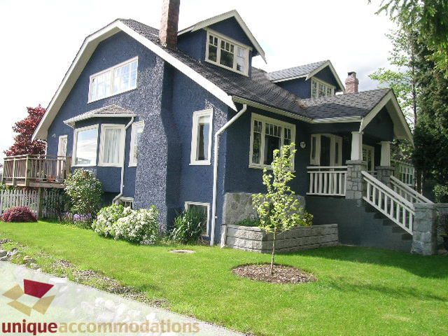 Spacious 5-bedroom suite in a charming blue house, featuring a wrap-around porch and lush green lawn. - 1505 Grand Blvd., North Vancouver