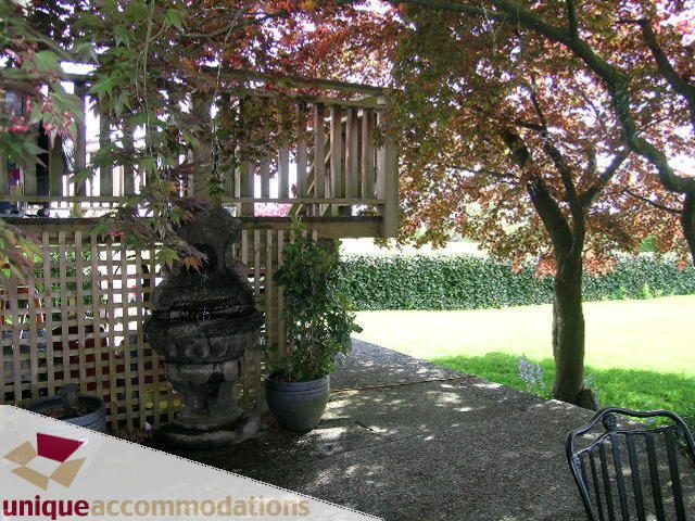 Furnished patio with wooden railing, potted plants, and garden view. - 1505 Grand Blvd., North Vancouver