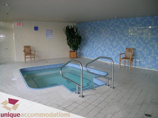 Spacious indoor pool area with tiled walls, wooden chairs, and a potted plant. - 3103 - 1033 Marinaside Crescent, Vancouver Downtown