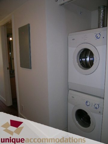 Laundry area with stacked washer and dryer, clean white walls. - 512-1216 Homer Street, Vancouver Downtown