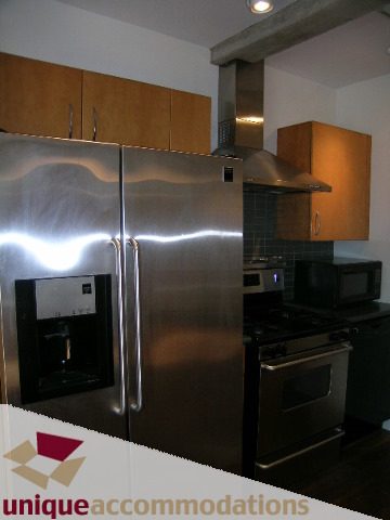 Bright kitchen with stainless steel appliances and wooden cabinets. - 512-1216 Homer Street, Vancouver Downtown