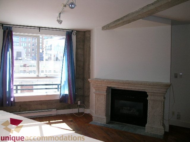 Loft with hardwood floors, city view, and a stone fireplace. - 512-1216 Homer Street, Vancouver Downtown