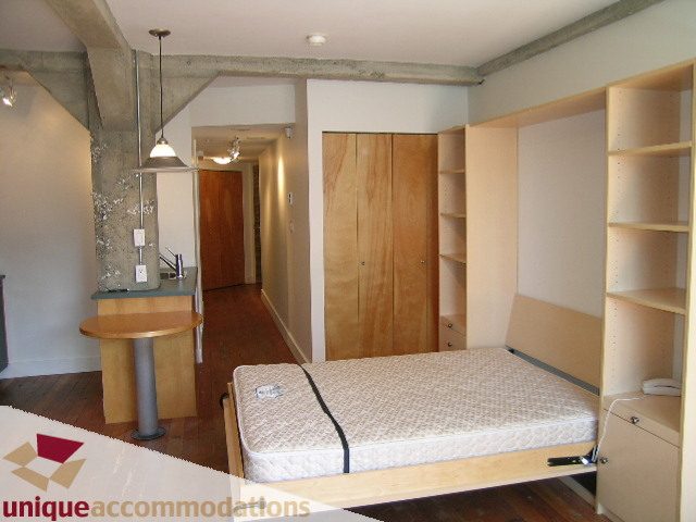 Loft with wooden furniture, open shelving, and a small table. - 512-1216 Homer Street, Vancouver Downtown