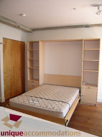 Furnished loft with built-in Murphy bed, wooden floors, and shelving. - 512-1216 Homer Street, Vancouver Downtown