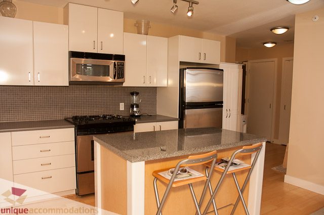 Bright kitchen with granite countertops and stainless steel appliances, featuring a modern design. - 508-155 West 1st Street, North Vancouver