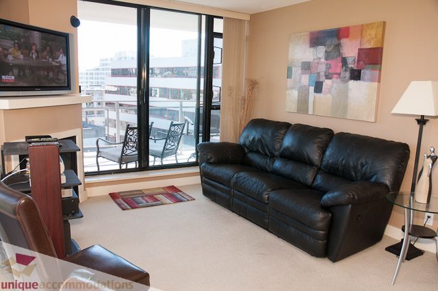 Furnished living room with black leather couch, city view, and modern decor. - 508-155 West 1st Street, North Vancouver