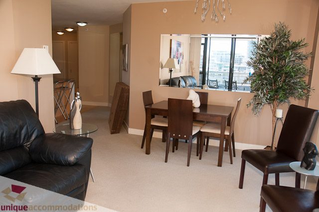 Furnished living and dining area with modern furniture, city view through large windows. - 508-155 West 1st Street, North Vancouver
