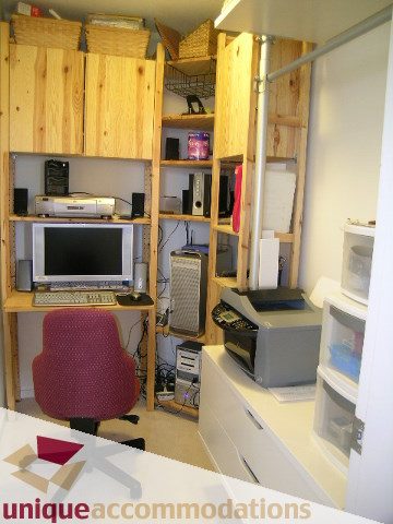 Bright and cozy den with wooden shelves, desk, and red chair, featuring a microwave and kitchenette. - 2001-1199 Seymour Street, Vancouver Downtown
