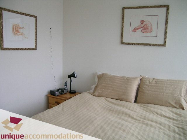 Bright bedroom with beige bedding and framed artwork on the walls. - 2001-1199 Seymour Street, Vancouver Downtown