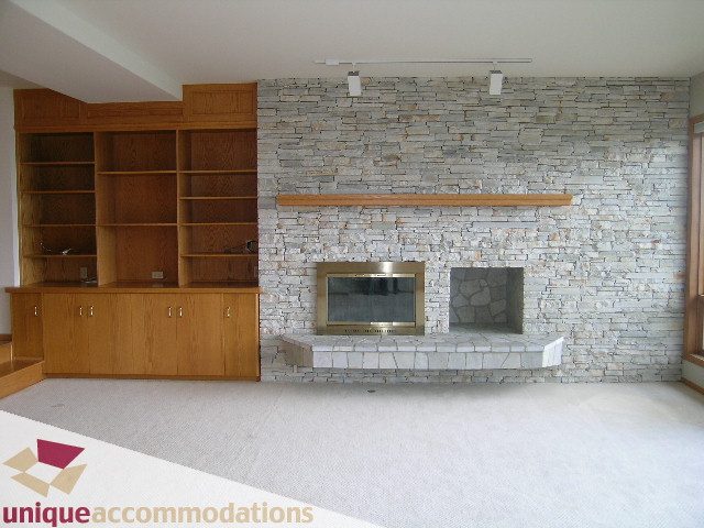 Bright living room with stone accent wall and built-in bookshelves. - 1472 Camridge Road, West Vancouver