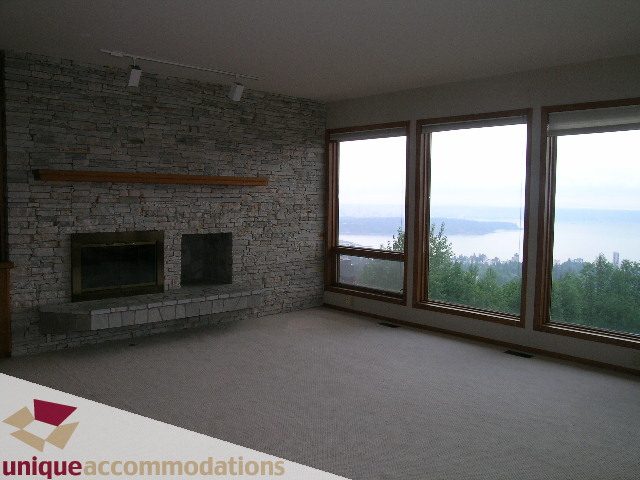 Spacious living room with stone fireplace and panoramic city view. - 1472 Camridge Road, West Vancouver
