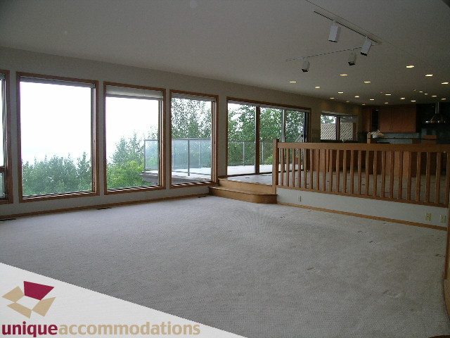 Bright living room with large windows, hardwood floors, and a view of greenery. - 1472 Camridge Road, West Vancouver