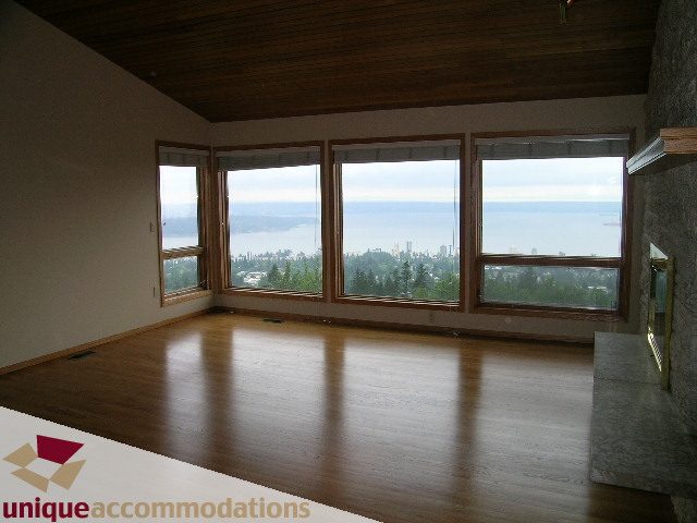 Furnished living room with hardwood floors, large windows, and a city view. - 1472 Camridge Road, West Vancouver