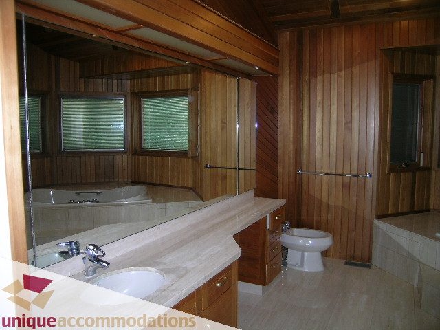 Furnished bathroom with wooden walls, marble countertop, and large mirror. - 1472 Camridge Road, West Vancouver