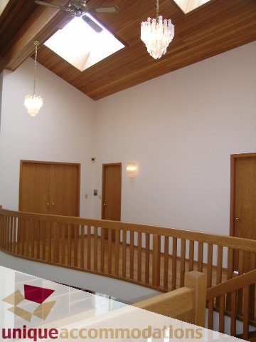 Staircase leading to upper level with wooden banister and skylight. - 1472 Camridge Road, West Vancouver
