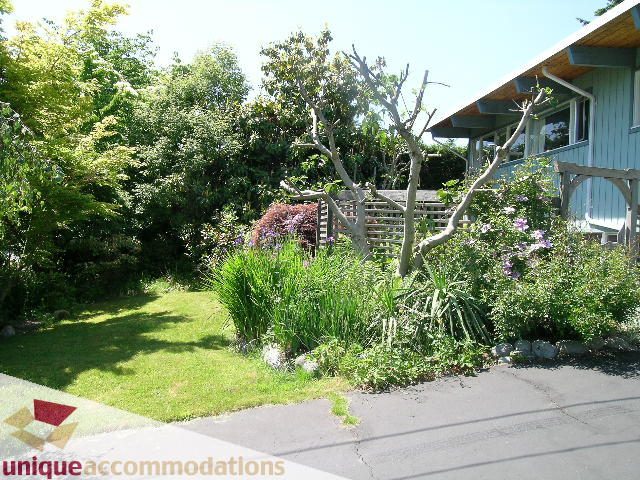 Furnished garden with lush greenery and a wooden fence. - 2556 Belloc Street, North Vancouver